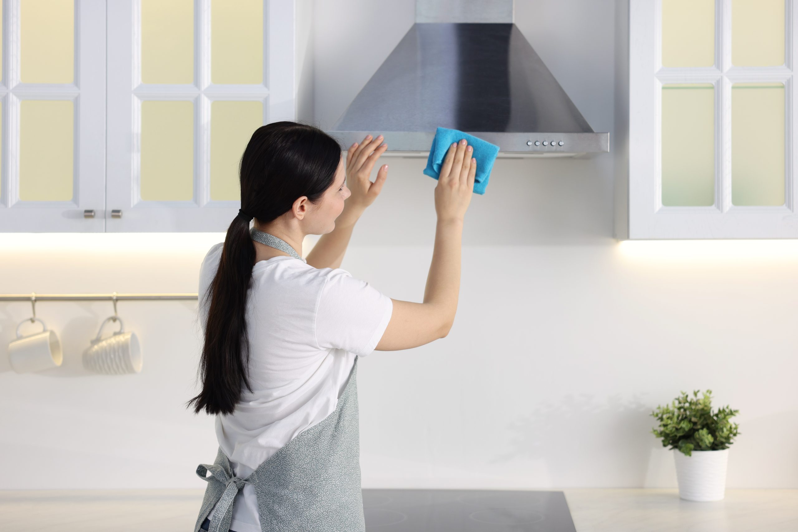 Spring cleaning. Woman wiping hood with rag in kitchen